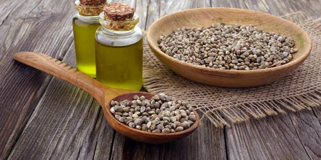 a bowl of hemp seeds and vials of oil